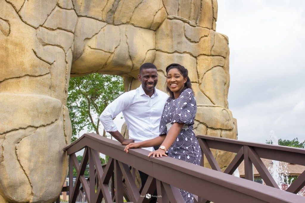 Couple standing close on a bridge with natural rock and trees in the background, representing partnership and emotional strength at home.