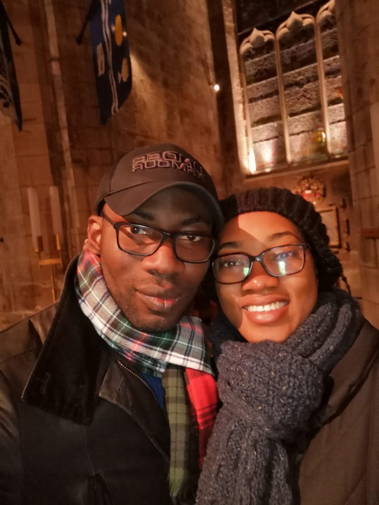 A handsome man and his beautiful wife holding each other closely and smiling beautifully.